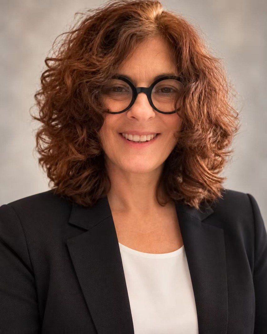 Dr. Nancy Wolf smiling, wearing glasses and a black jacket
